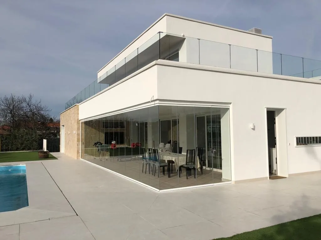 Porche de un chalet en Vizcaya cerrado con aluminio blanco y vidrio de seguridad, junto a la piscina