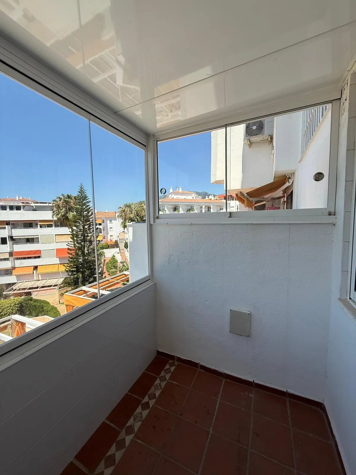 Esquina de una terraza cerrada con paños de vidrio y perfiles de aluminio blanco